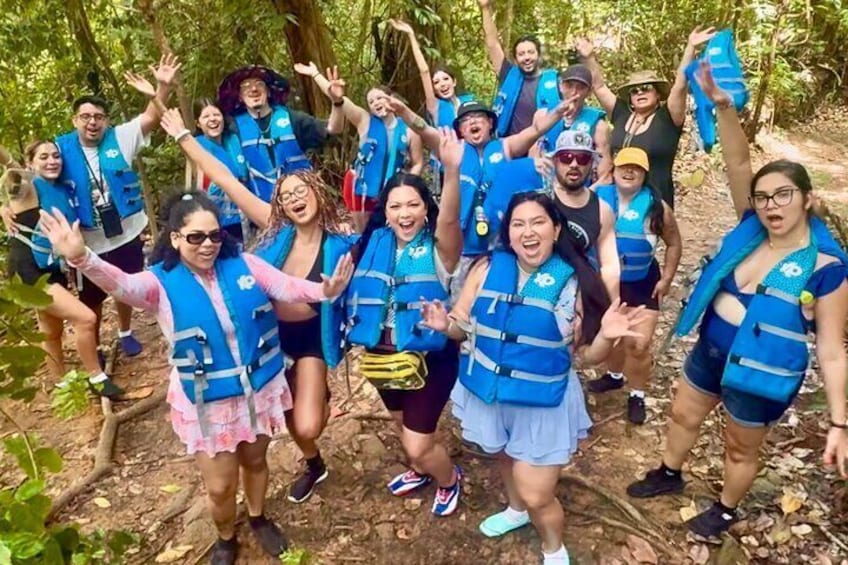 A group of people in blue life vests posing in a forest. 3