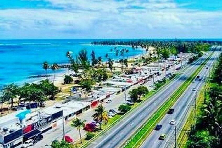 A coastal highway with vehicles, a beach, and palm trees. 5