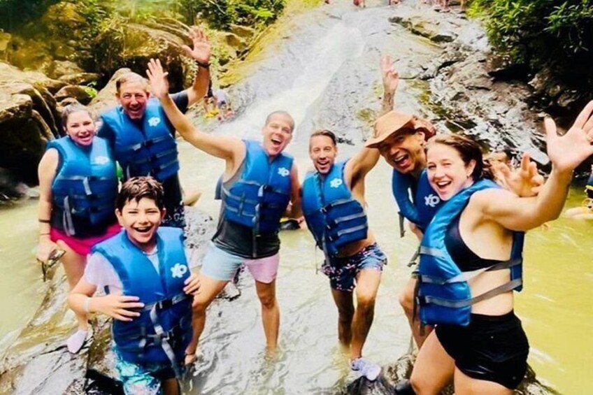 Un grupo de personas con chalecos salvavidas azules en la orilla rocosa de un río. 3