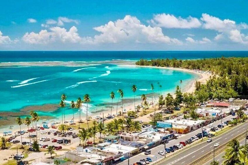 A coastal town with a beach, clear blue waters, and palm trees. 4