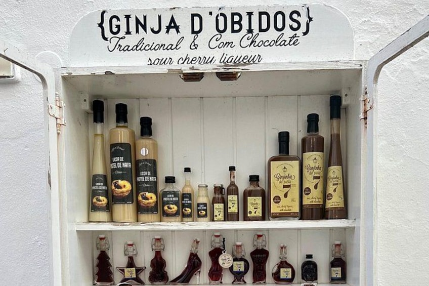 Une étagère où sont rangées différentes bouteilles de gin et de liqueurs, notamment du « Ginja D’Obidos » et du « Com Chocolate ». 2