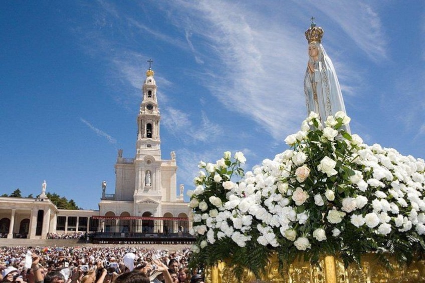 Une foule nombreuse, une église blanche dotée d’un clocher et une statue d’une figure religieuse. 4