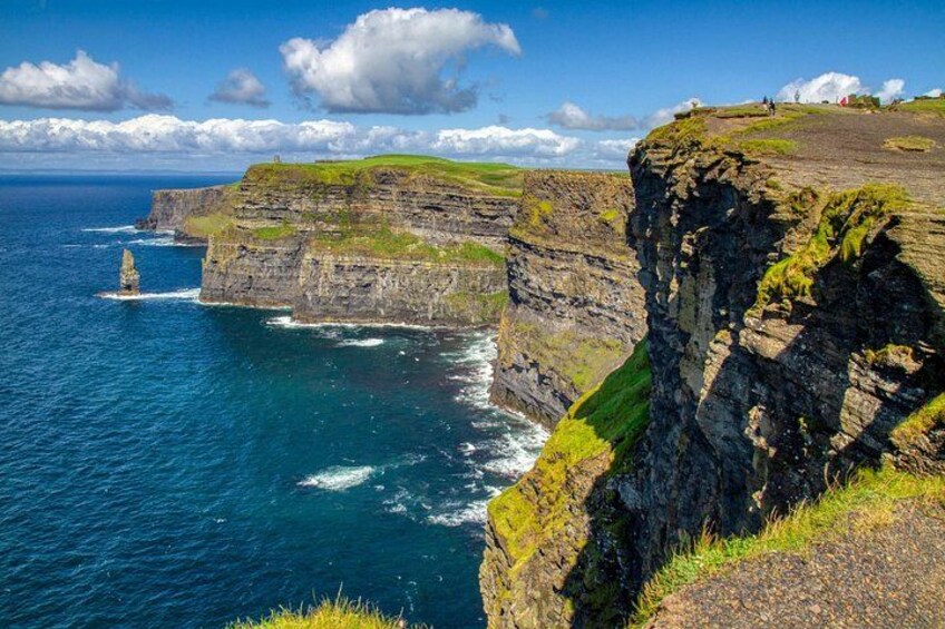 A coastal cliff with a lighthouse, ocean waves, and a grassy cliff top. 3