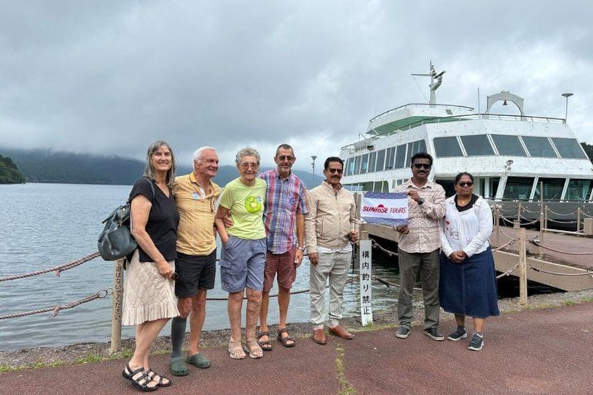 A group of people standing by a dock with a boat in the background. 3