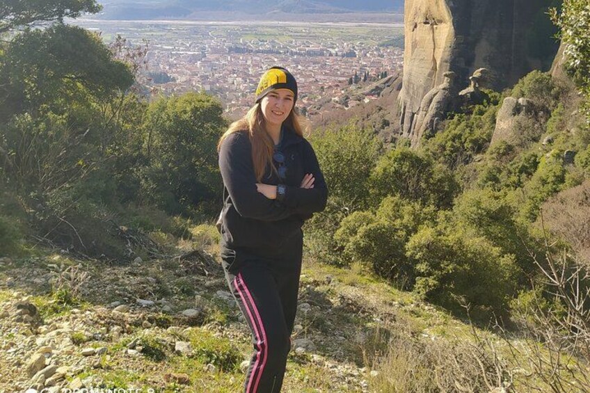 Una persona de pie sobre una colina rocosa, con un paisaje urbano al fondo. 3