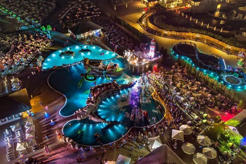 An aerial view of a water park at night with illuminated slides and pools. 4