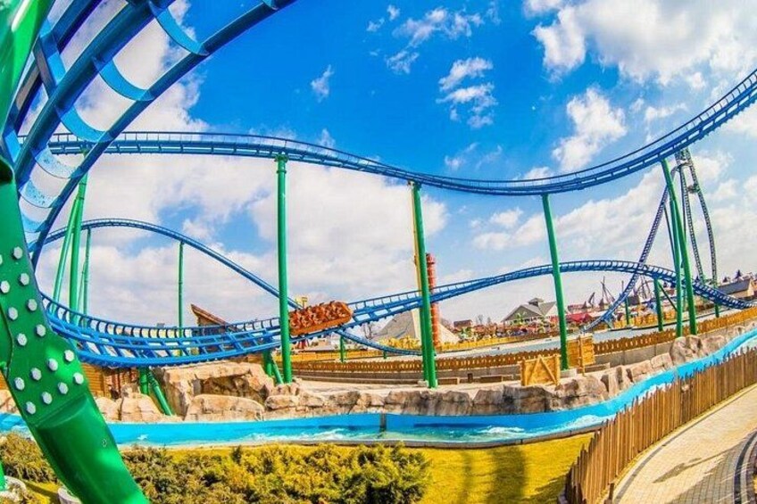 A roller coaster with blue tracks and green supports, set against a clear blue sky. 3