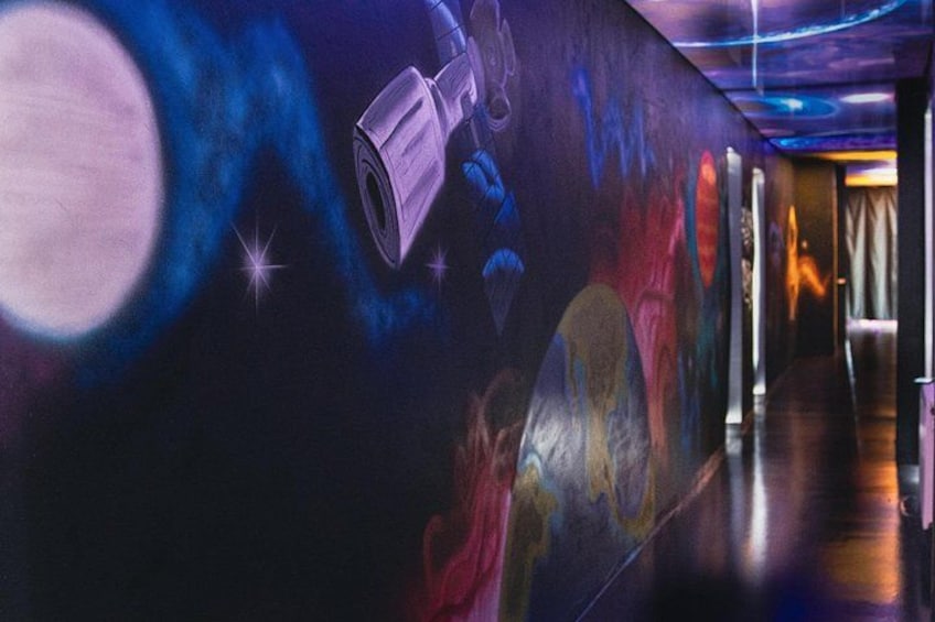 Un couloir orné d’une fresque représentant une scène spatiale, avec notamment un télescope et des planètes. 2