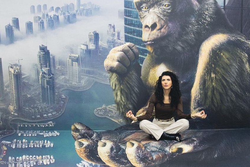 Une personne médite, assise sur un grand poisson, avec une vue sur une ville en arrière-plan et un gorille également visible. 5