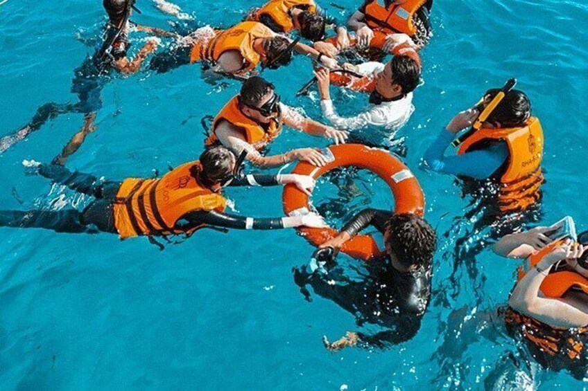 Des personnes dans une piscine, portant des gilets de sauvetage orange et tenant un cercle de sauvetage. 2