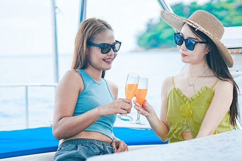Dos personas en un bote, sosteniendo bebidas, con una masa de agua y vegetación al fondo. 2