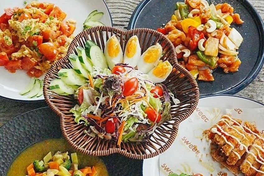Diverse gerechten, waaronder een salade, roerbakgroenten en een gepaneerd gerecht. 4