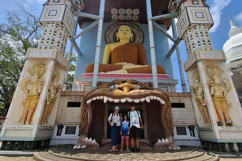Eine große Buddha-Statue, aufwendige Tempelarchitektur und zwei Personen im Vordergrund. 2