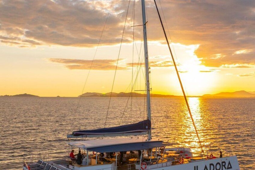A sailboat named 'Iladora' with a mast and sails, on calm waters during sunset. 2