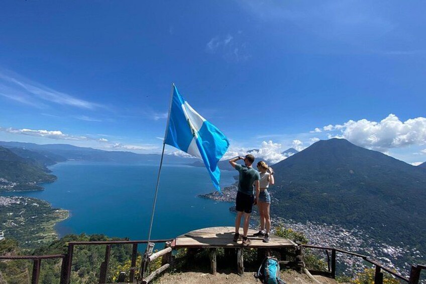 A flag on a platform overlooking a body of water and a mountain. 4