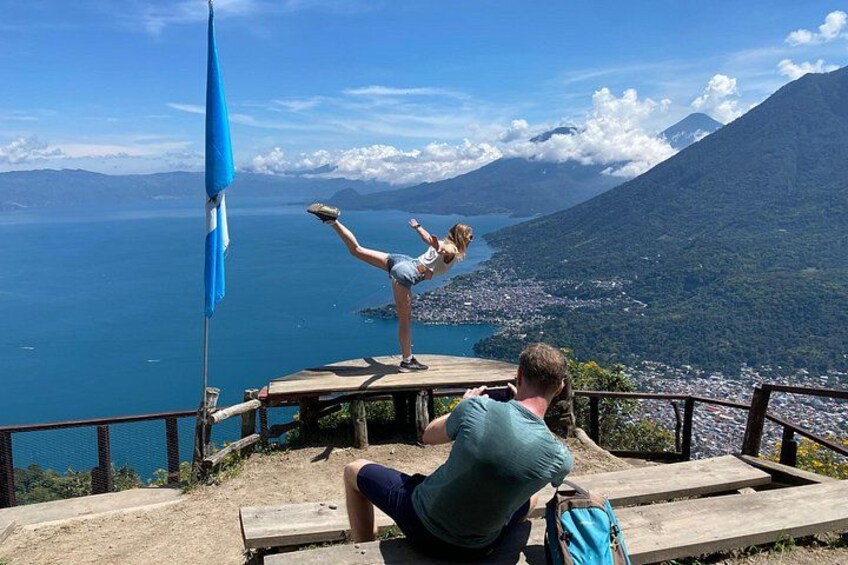 A person performing a handstand on a wooden platform with a scenic view of a lake and mountains in the background. 3