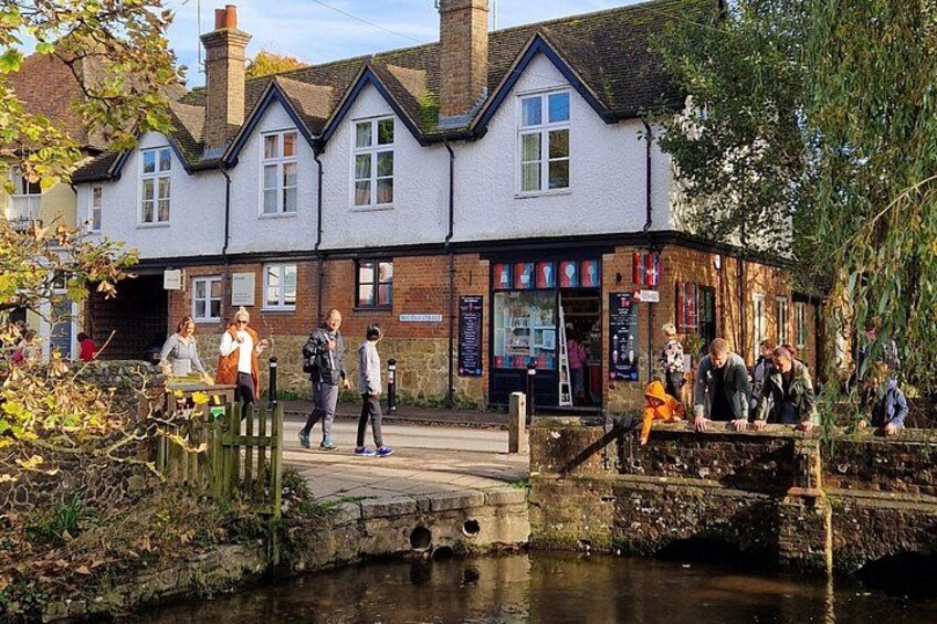 A riverside scene with a pub, people walking, and a bridge. 4