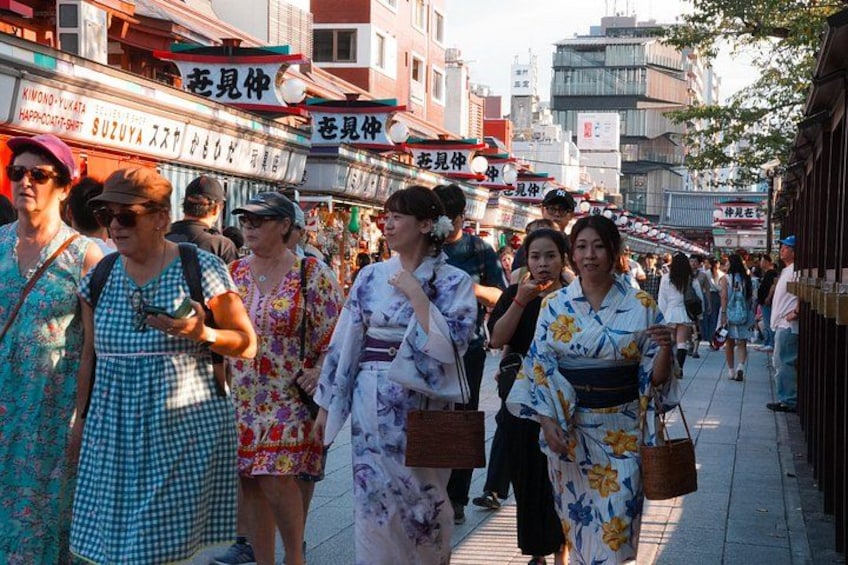 Eine belebte Straße mit Fußgängern, manche tragen traditionelle japanische Kleidung. 2
