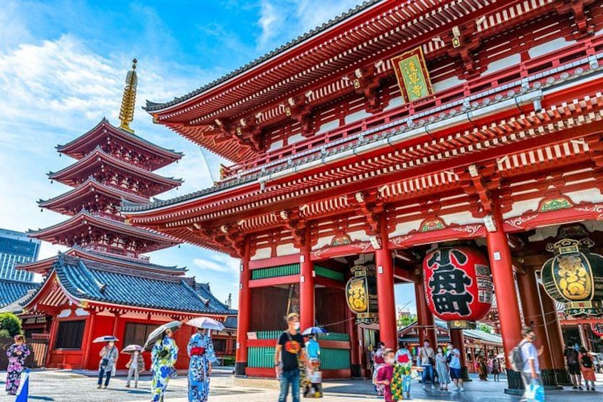 Un tempio tradizionale giapponese con architettura rossa e oro, una pagoda e persone che passeggiano. 1