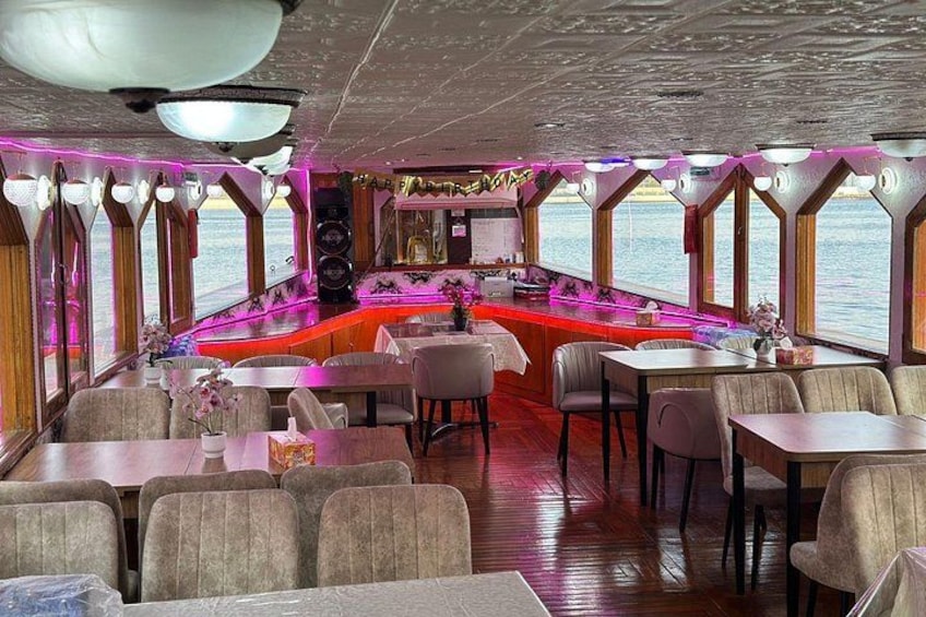 A restaurant with tables and chairs, a bar area, and large windows overlooking the sea. 2
