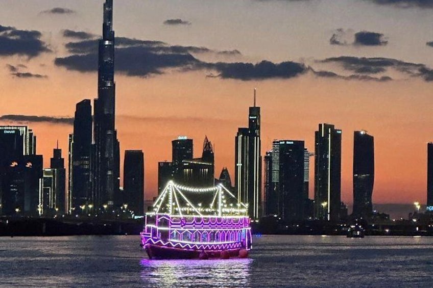 A brightly lit boat with intricate designs on a body of water, with a city skyline in the background. 5