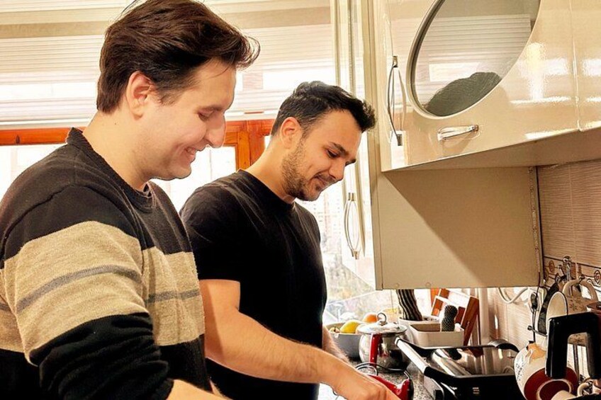 Deux personnes sont en train de cuisiner dans une cuisine équipée d’une cuisinière, de casseroles et d’ustensiles. 3