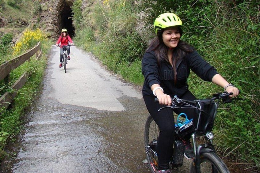 Twee fietsers op een smal, nat pad, omringd door begroeiing. 4
