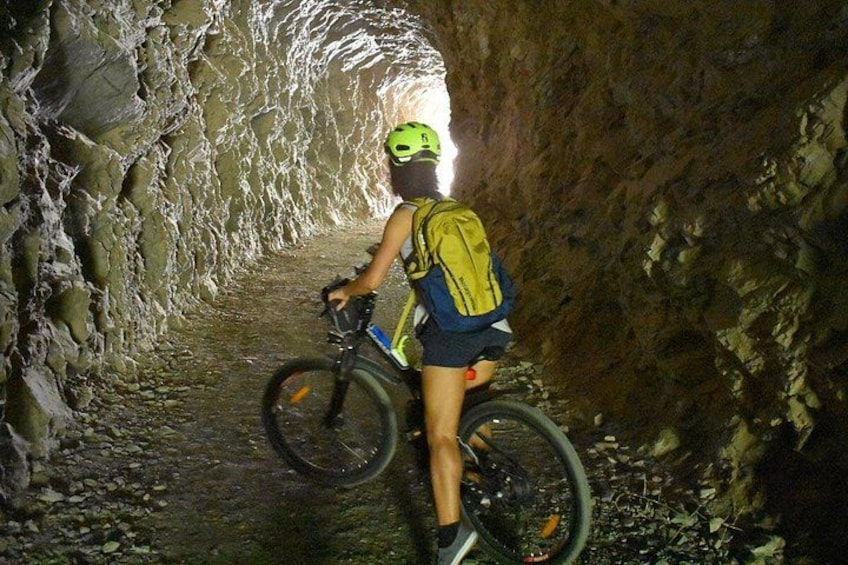 Iemand fietst door een smalle, rotsachtige tunnel. 3