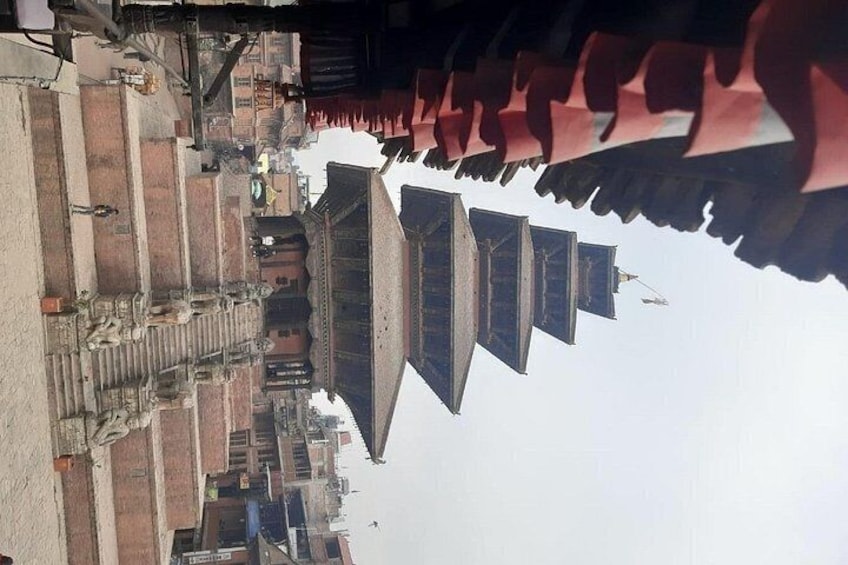 A traditional building with multiple tiers and a red roof, surrounded by a courtyard with steps and stone walls. 3