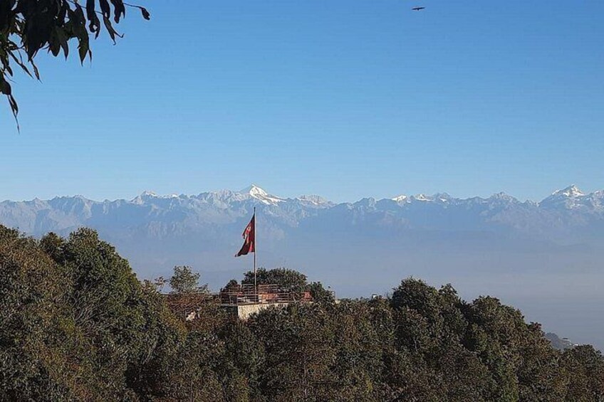 A flag on a hilltop with a mountain range in the background. 4