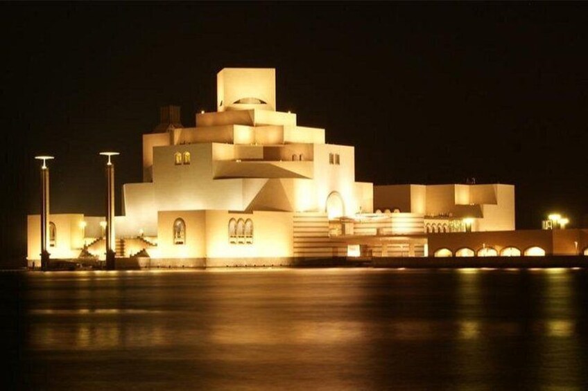 Ein modernes Gebäude mit einzigartigem architektonischen Design, das sich durch mehrere Ebenen und einen markanten, zentralen Turm auszeichnet, beleuchtet in der Nacht. 2