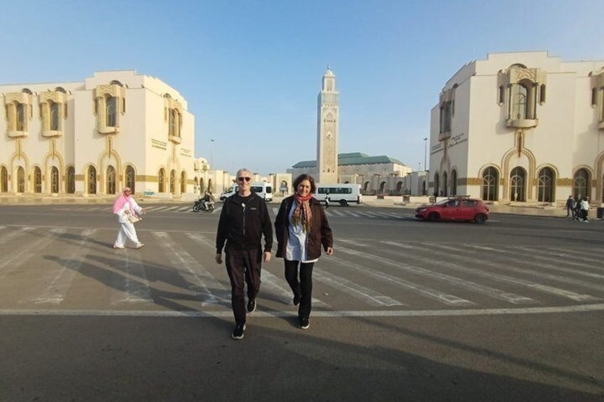 A wide street with historic buildings, a minaret, and a red car. 3