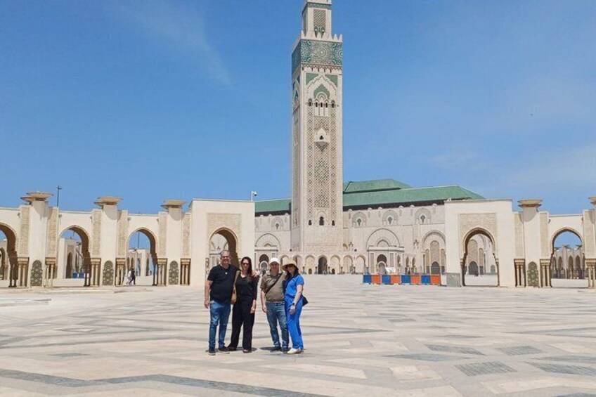 A group of people standing in front of a large mosque with a tall minaret. 1