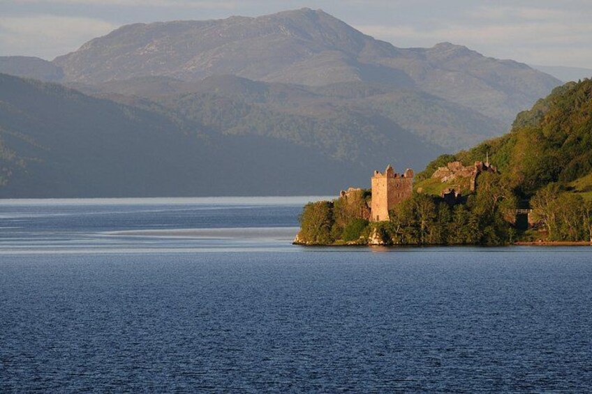 Un castillo en una pequeña isla rodeada de agua y montañas. 2