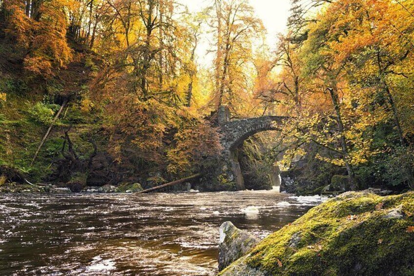 Un puente de piedra sobre un río, rodeado de follaje otoñal. 3