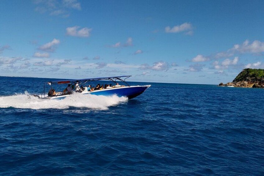 A blue speedboat with passengers on a clear day. 3