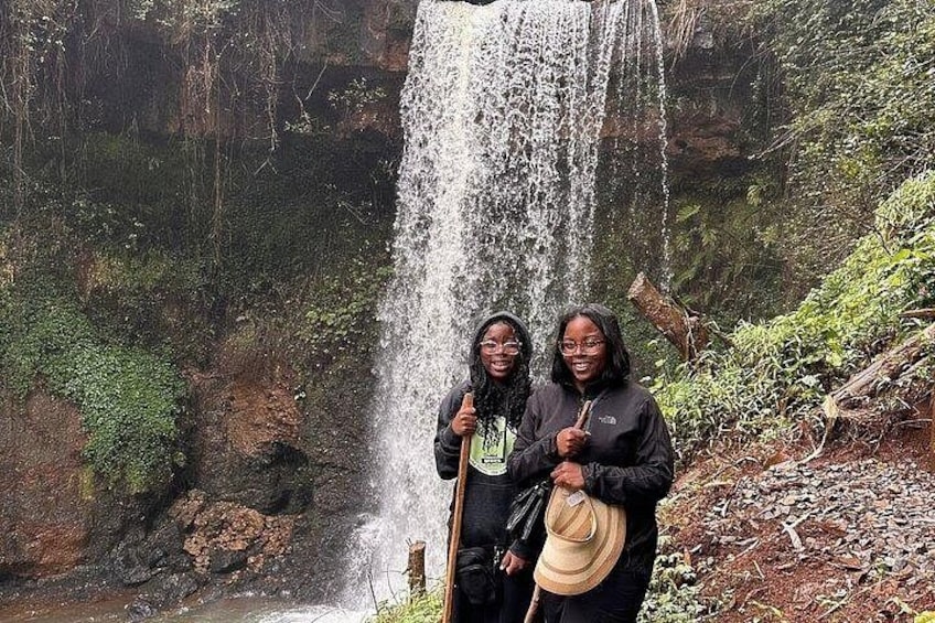 A waterfall with two people standing in front of it. 2