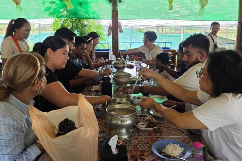A group of people dining at a long table with food and utensils. 2