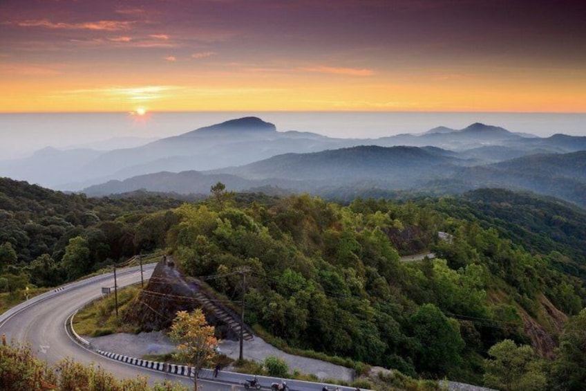 A winding road through a mountainous landscape with a sunset in the background. 3