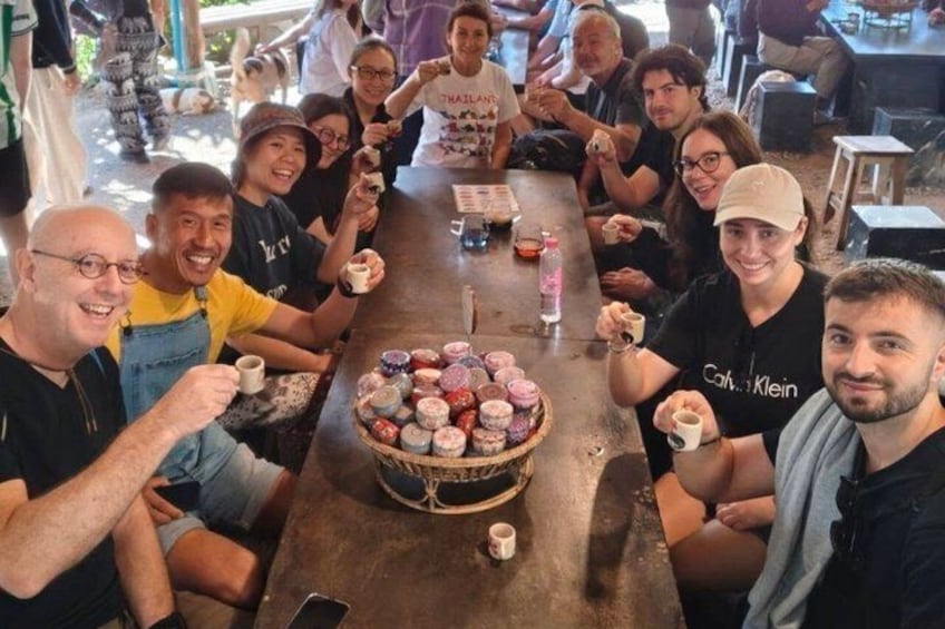 A group of people sitting around a table with a variety of pastries and drinks. 4