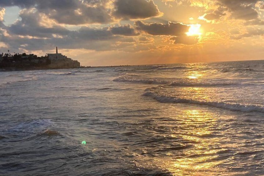 A sunset over the ocean with waves and a distant shoreline. 5