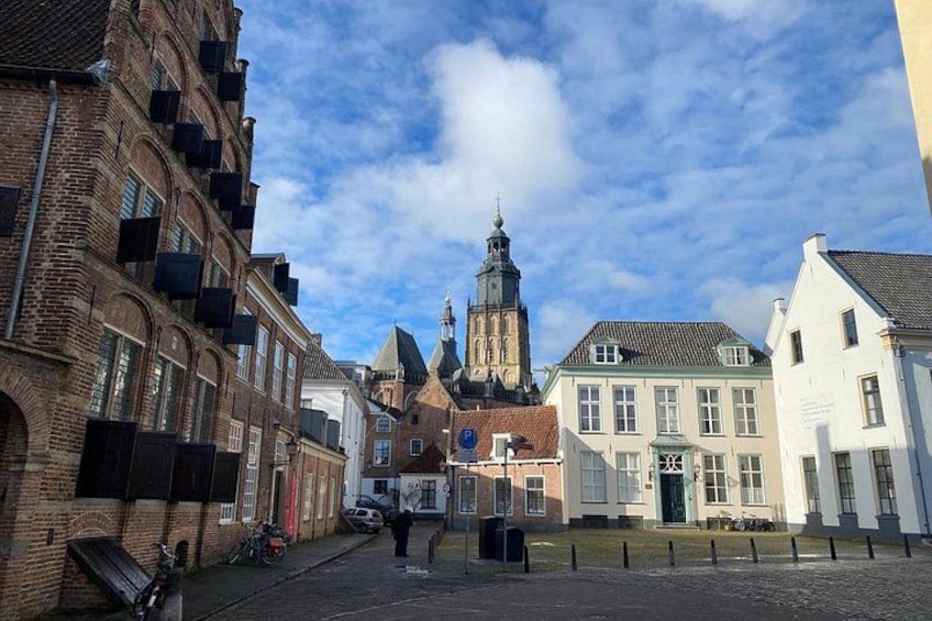 A cobblestone street with historic buildings, a church tower, and a bicycle. 2