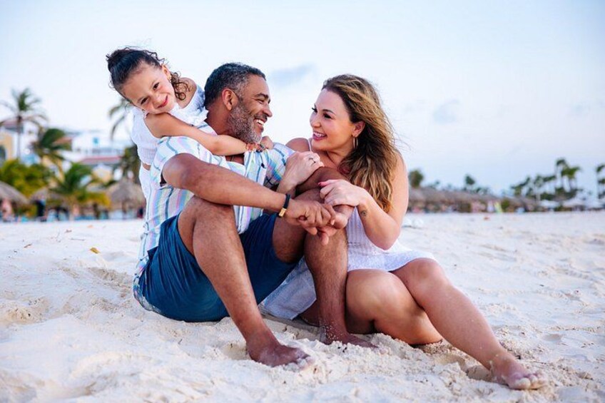 En familie på en sandstrand med palmer i baggrunden. 4