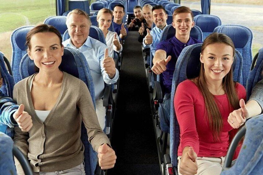 A bus interior with passengers seated and giving thumbs up. 4