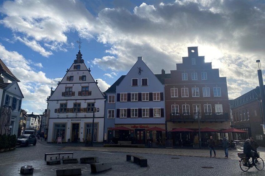 A cobblestone street with historic buildings, a bicycle, and a clear sky. 2