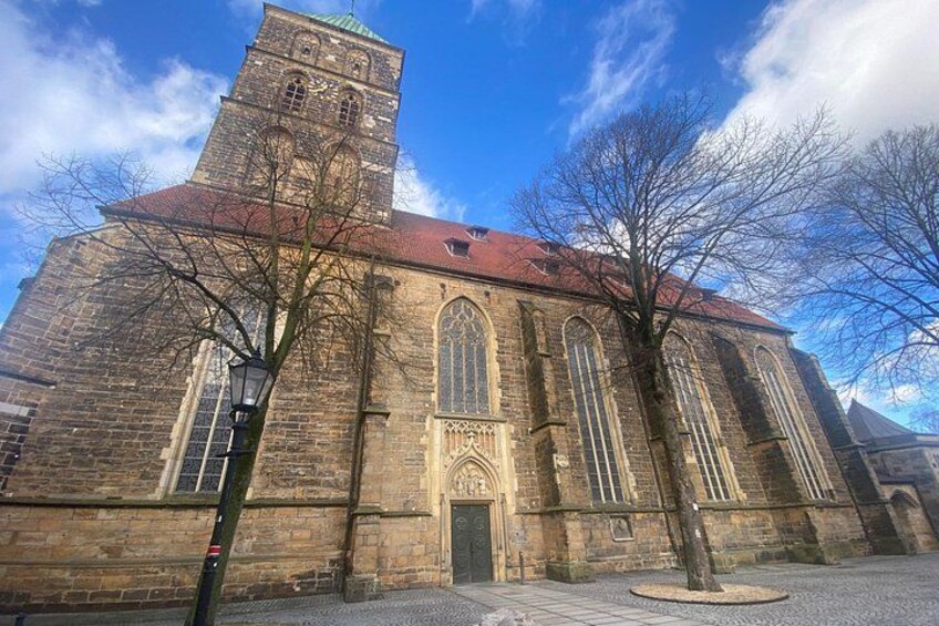 A historic church with a tall tower, large arched windows, and a red roof. 4