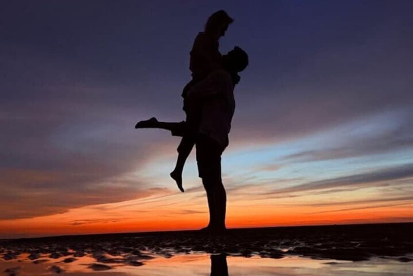 La silhouette d’une personne tenant un enfant dans ses bras, sur fond de coucher de soleil à la plage. 4