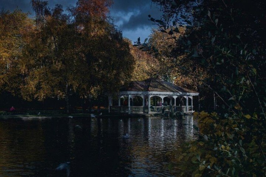 A gazebo by a lake surrounded by autumn trees. 2