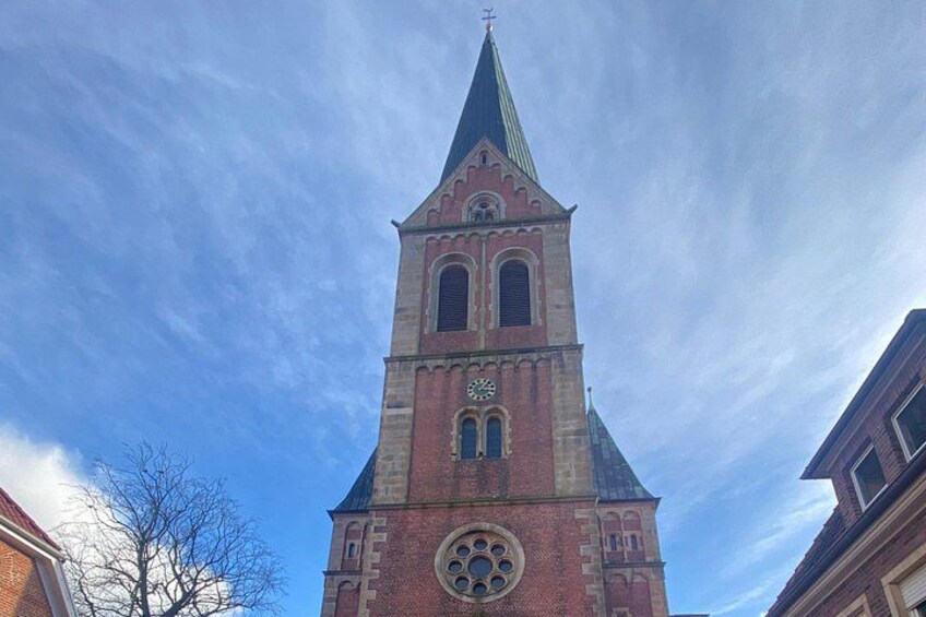 Un'alta chiesa in mattoni con una torre dell'orologio e un campanile a guglia. 4