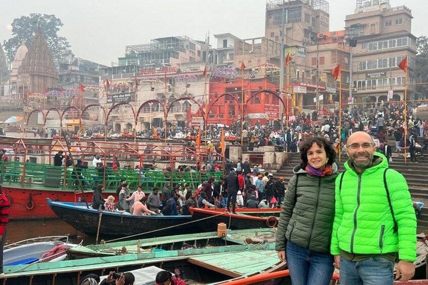 A crowded riverside with boats, a temple, and people. 3